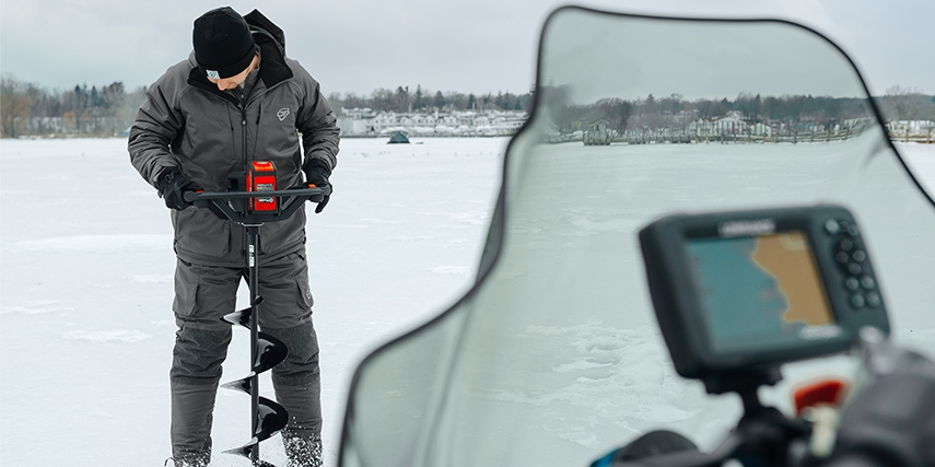 anglers using a motorized auger to drill holes in the ice
