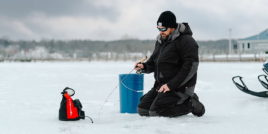 Man sitting on his knees while ice fishing 