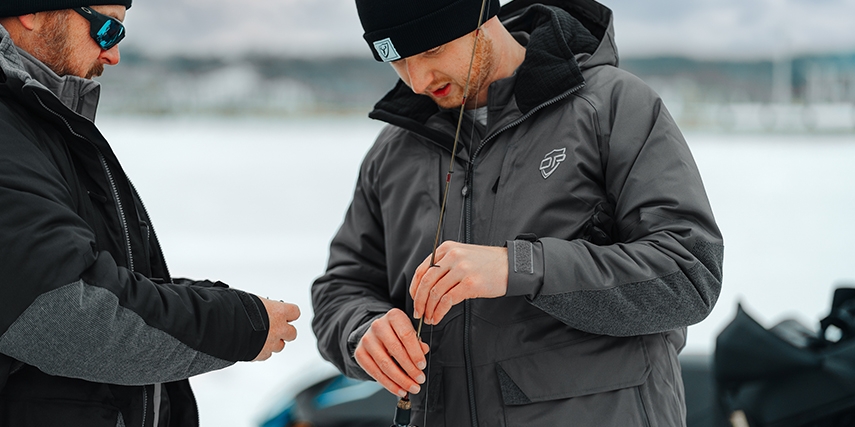 two anglers prepping their rods for ice fishing wearing outdoor pursuit