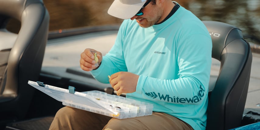 Man going through his lures while fishing and wearing whitewater tech hoodie