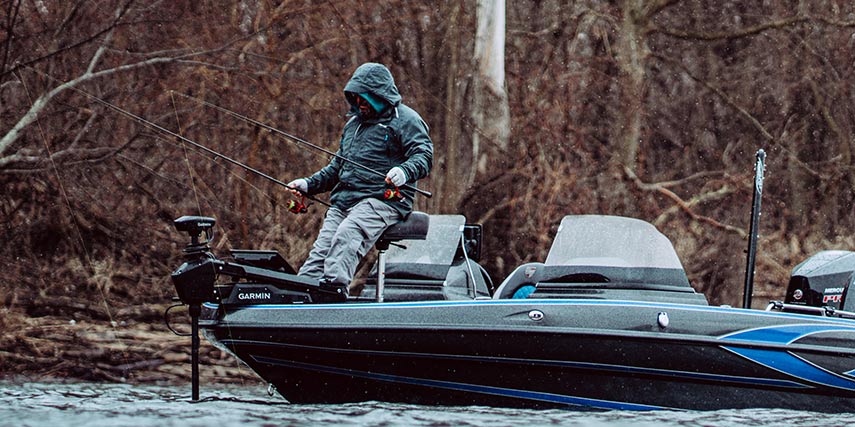 Man fishing off the bow of his boat wearing Great Lakes Rain jacket and bibs