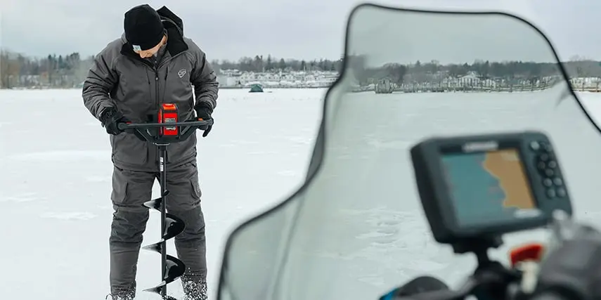 anglers using a motorized auger to drill holes in the ice
